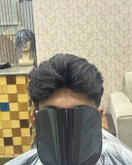 شعر داكن مموج متوسط الطول مصفف إلى الجانب لعميل بعد تركيب نظام الشعر، والوجه مغطى بمرآة