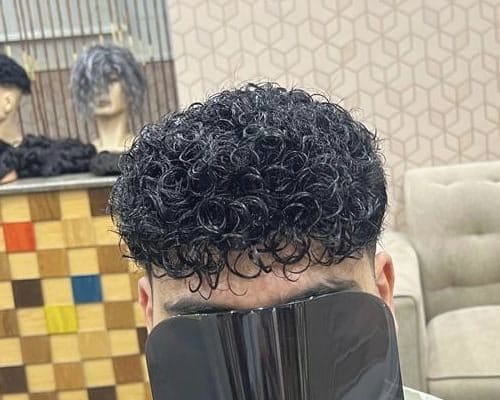 عميل من مركز الشام بعد تركيب نظام شعر طبيعي المظهر: شعر كيرلي داكن كثيف بخصلات صغيرة متماسكة، ووجهه مغطى بمرآة سوداء